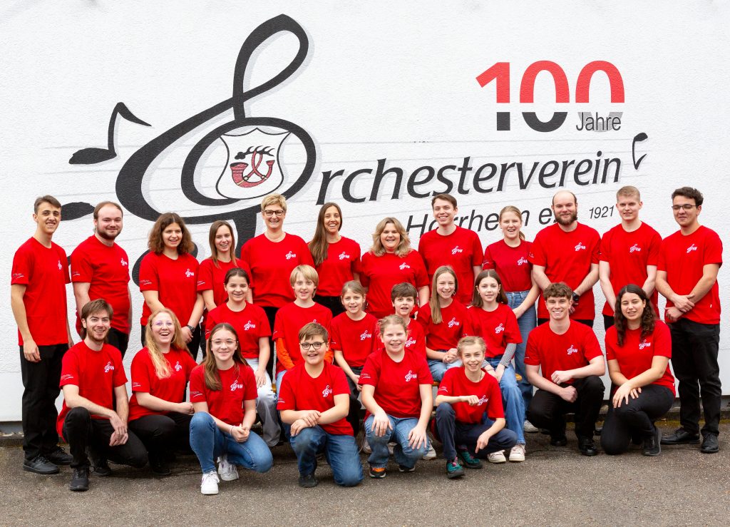 Die Jugendkapelle vor dem Logo des Vereinsheims in roten T-Shirts